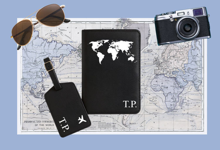 Schwarze Reisepasshülle mit Weltkarten-Design und personalisierten Initialen, dazu passender Kofferanhänger mit Flugzeug-Symbol – elegantes Reise-Set aus Kunstleder, ideal als Geschenk für Weltenbummler.