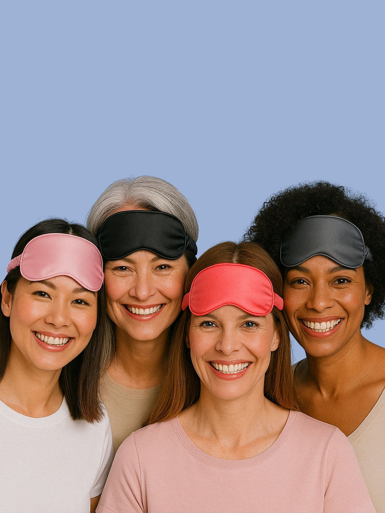 Vier Frauen mit Schlafmasken in verschiedenen Farben lachen in die Kamera – personalisierbare Satin-Schlafmasken in Rosa, Schwarz, Rot und Grau.