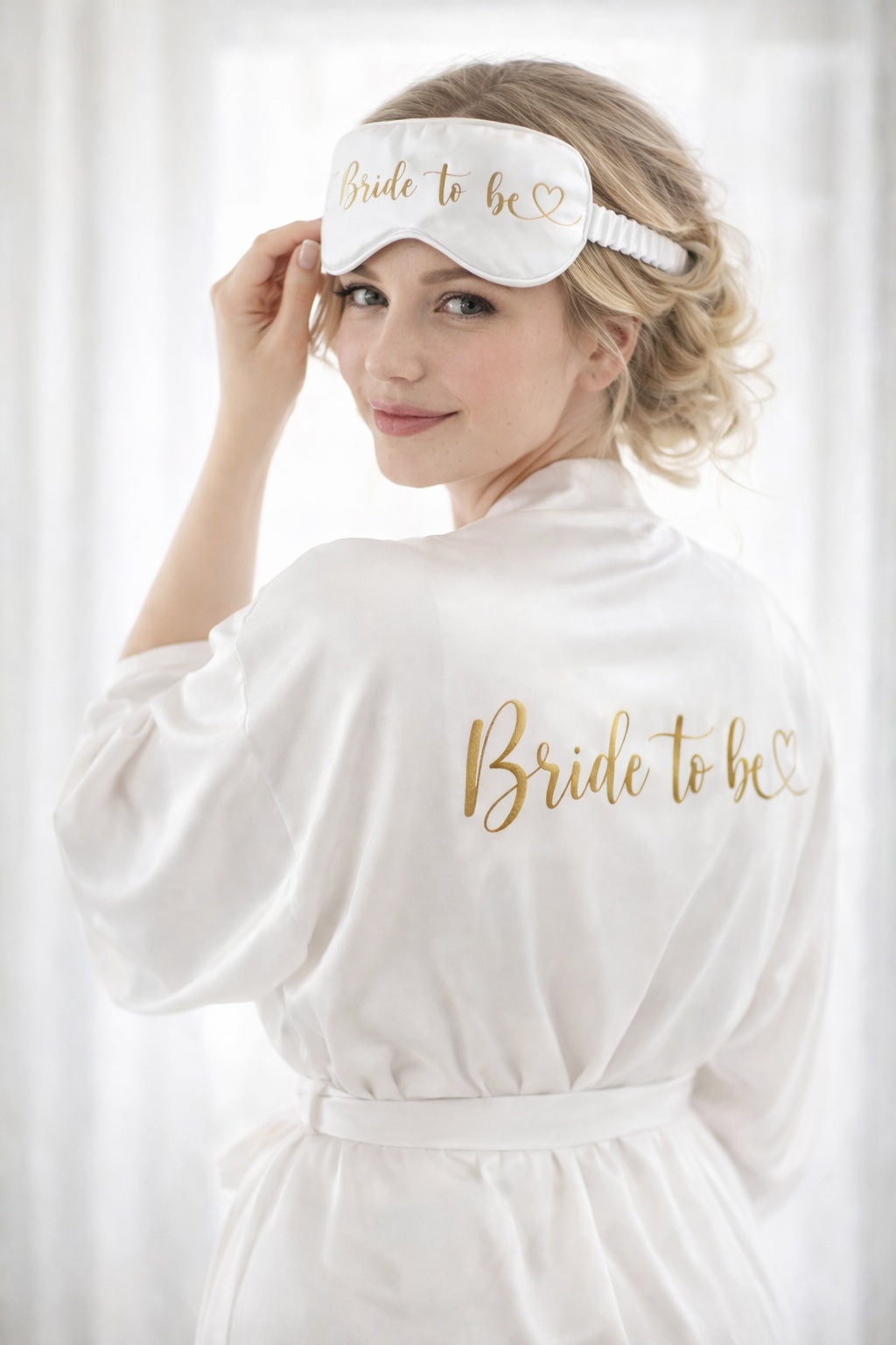 Braut beim Getting Ready mit weißem Morgenmantel und Schlafmaske mit goldener Aufschrift „Bride to be“.