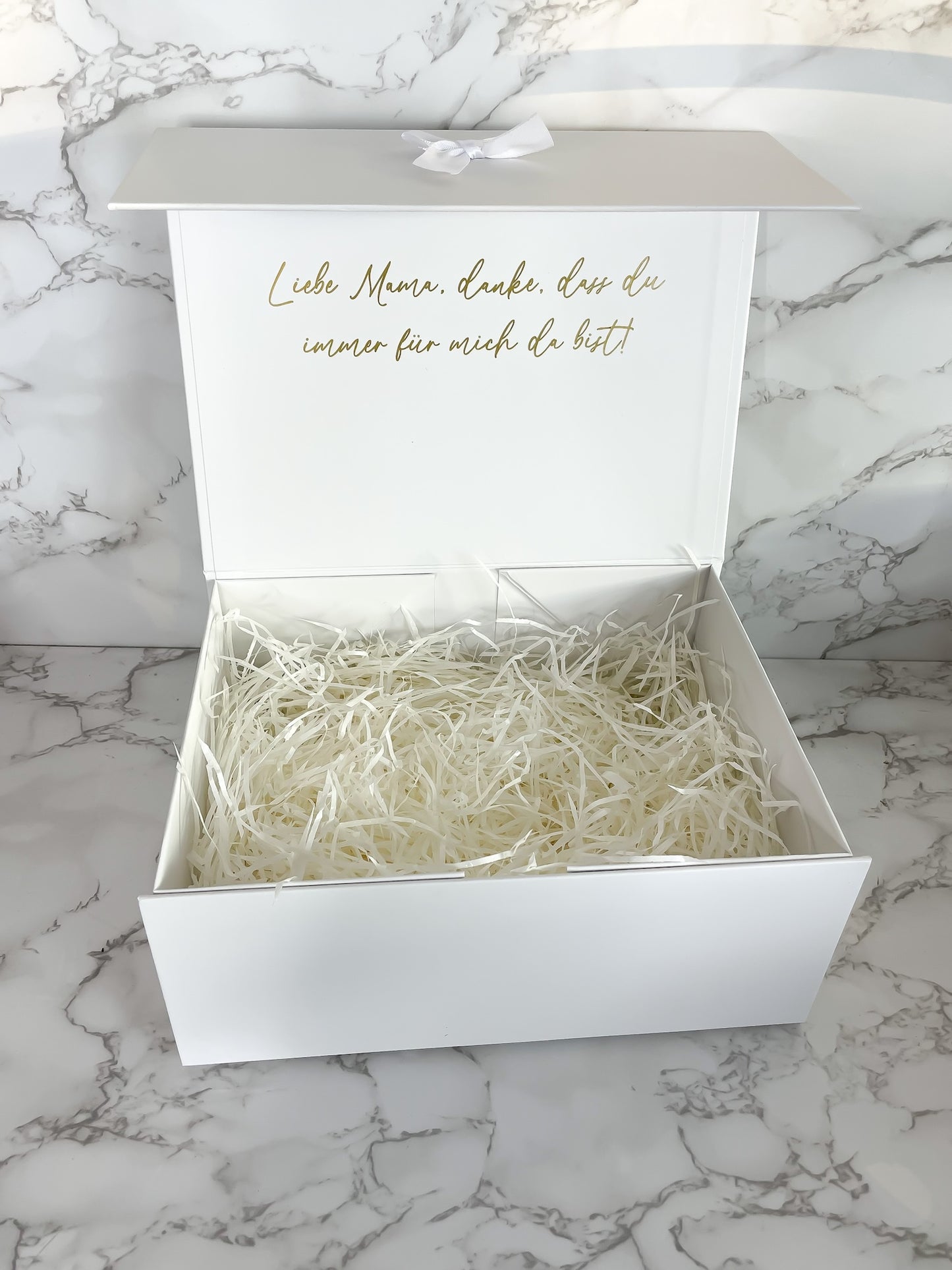 Geöffnete weiße Geschenkbox für die Brautmama mit goldener Botschaft im Deckel und dekorativer Füllung, liebevoll gestaltet als Hochzeitsgeschenk.