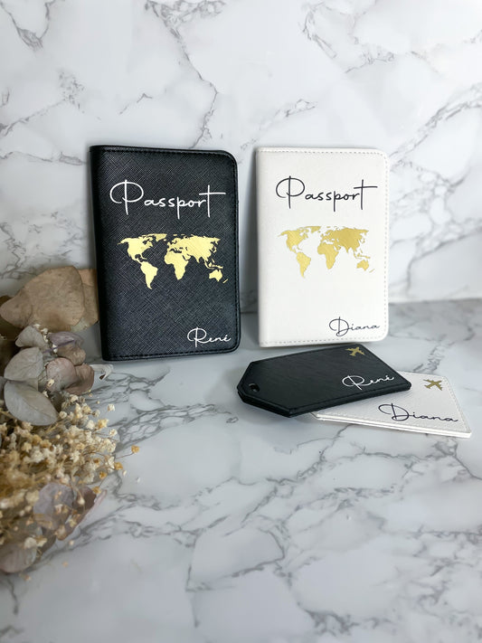 Personalisierte Reisepasshüllen aus veganem Saffiano-Leder – in Schwarz und Weiß mit goldener Weltkarte und Schriftzug „Passport“, dazu passende Kofferanhänger mit Namen „Reni“ und „Diana“, dekorativ auf Marmor-Hintergrund.