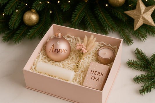 Rosa Geschenkbox zu Weihnachten mit roségoldener Christbaumkugel ‚Anna‘, rosa Trockenblumenstrauß, roséfarbener Kerze im Glas und rosafarbenen Tee.