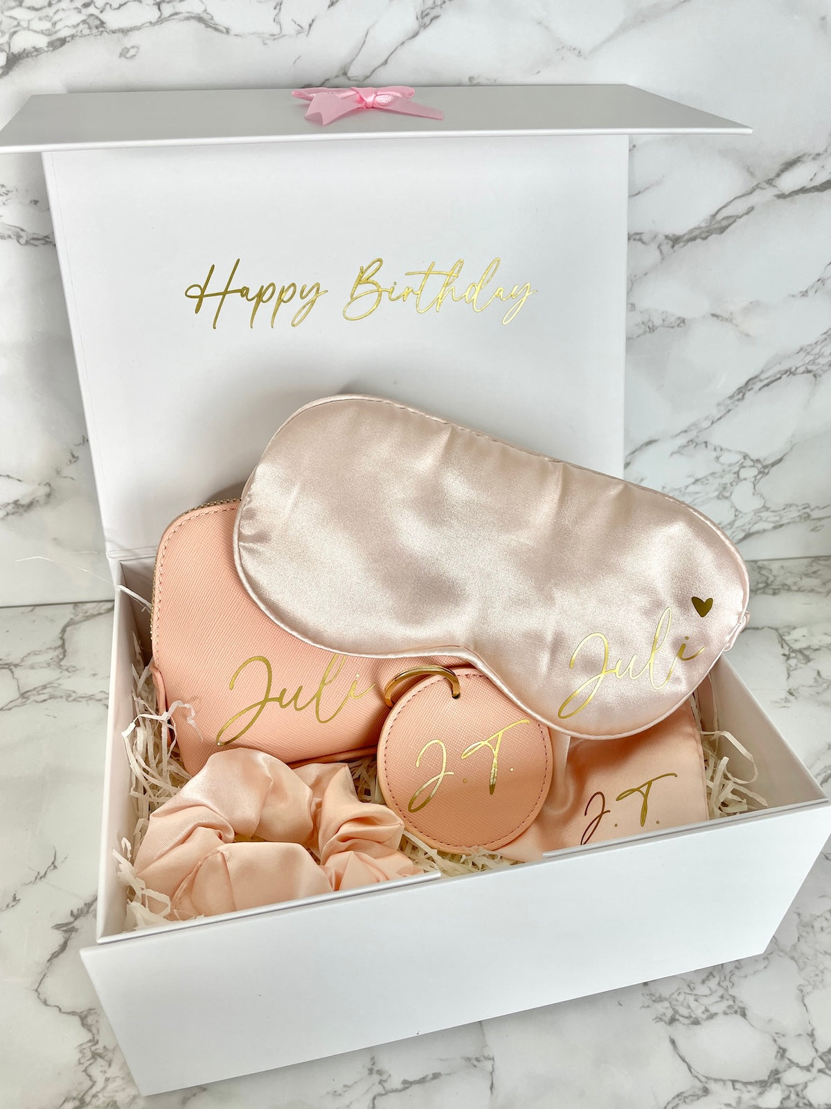 Personalisierte Geschenkbox für Frauen mit Kosmetiktasche, Schlafmaske, Scrunchie und Schlüsselanhänger in Rosa.