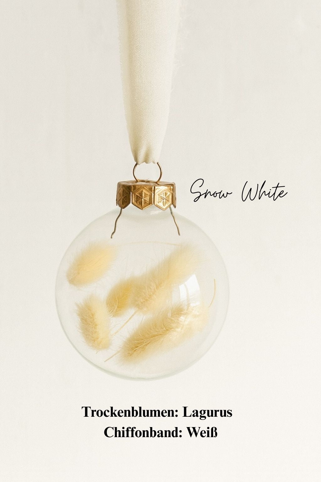 Personalisierte Weihnachtskugel aus Glas mit goldenem Kranz und weißen Chiffon-Aufhänger, gefüllt mit weißen Lagurus-Trockenblumen, Variante ‚Snow White‘.