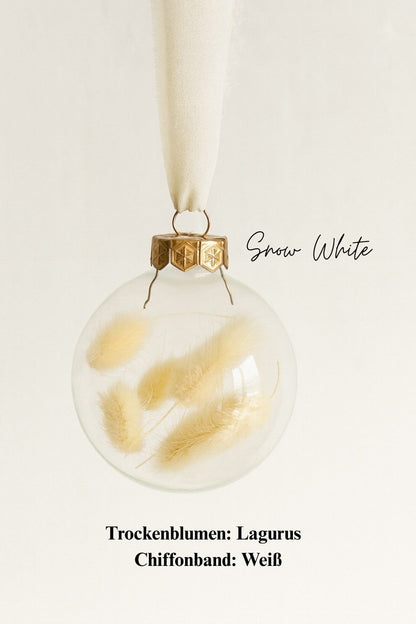 Personalisierte Weihnachtskugel aus Glas mit goldenem Kranz und weißen Chiffon-Aufhänger, gefüllt mit weißen Lagurus-Trockenblumen, Variante ‚Snow White‘.