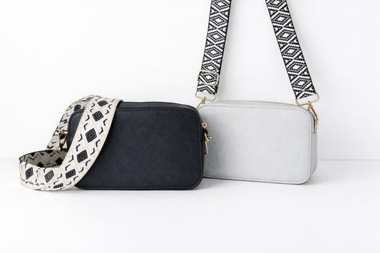 Moderne Crossbody Tasche für Damen in Schwarz und Grau mit breitem verstellbarem Schulterriemen und goldenen Details auf hellem neutralem Hintergrund.