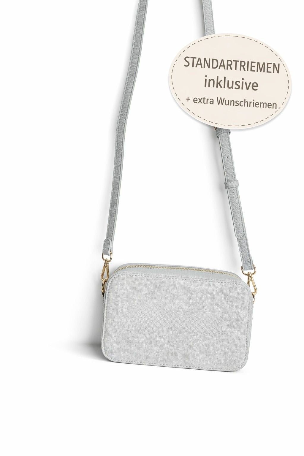 Graue Crossbody Tasche mit Standardriemen, inklusive zusätzlichem Wunschriemen zur Auswahl, auf hellem neutralem Hintergrund.
