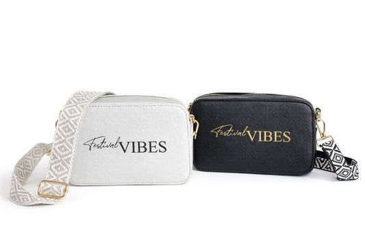 Zwei Damen Umhängetaschen „Festival Vibes“ in Schwarz und Grau mit breitem Taschengurt auf hellem neutralem Hintergrund.