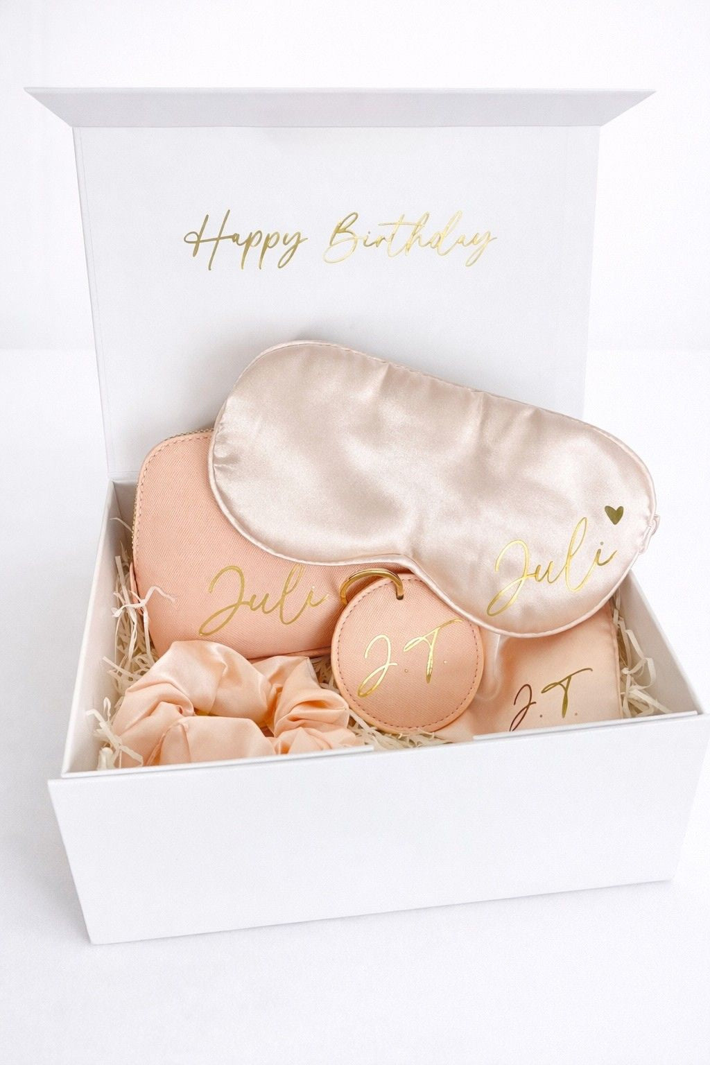 Offene weiße Geschenkbox mit personalisiertem Geburtstags-Set in Rosa: Kosmetiktasche, Schlafmaske, Scrunchie, Schlüsselanhänger und Satinbeutel