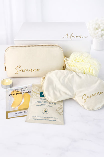 Wellness-Geschenkbox „Mama“ mit personalisierter Kosmetiktasche und Schlafmaske „Susanne“, Augenpads, Peeling, Duschschwamm und Teelicht auf hellem Hintergrund