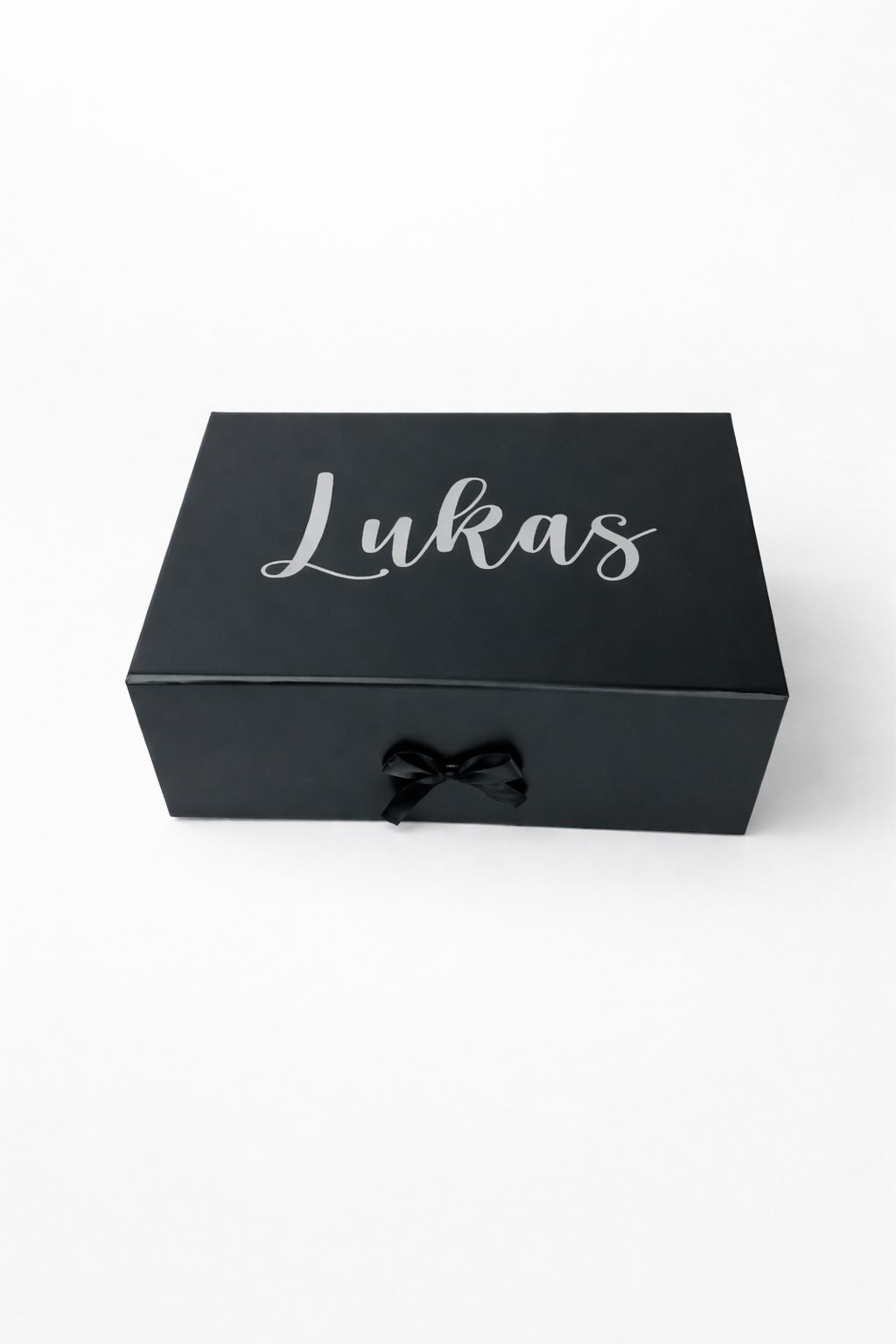 Schwarze, personalisierte Geschenkbox mit Name ‚Lukas‘ in silberner Schrift auf hellem, minimalistischem Hintergrund.“
