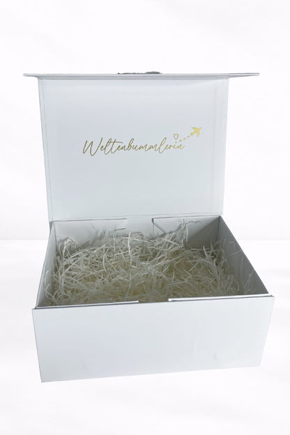Weiße Geschenkbox "Weltenbummlerin" geöffnet mit Füllmaterial