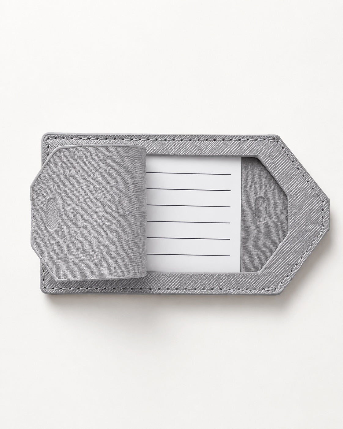 Hellgrauer Kofferanhänger mit sichtbarem Adress-Einleger auf hellem, neutralem Hintergrund in minimalistischer Produktaufnahme.