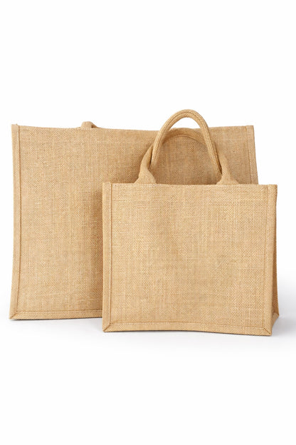 Zwei natürliche Jute Strandtaschen ohne Aufdruck in unterschiedlichen Größen vor hellem neutralem Hintergrund, robuste Beach Bags aus Jute mit stabilen Griffen.