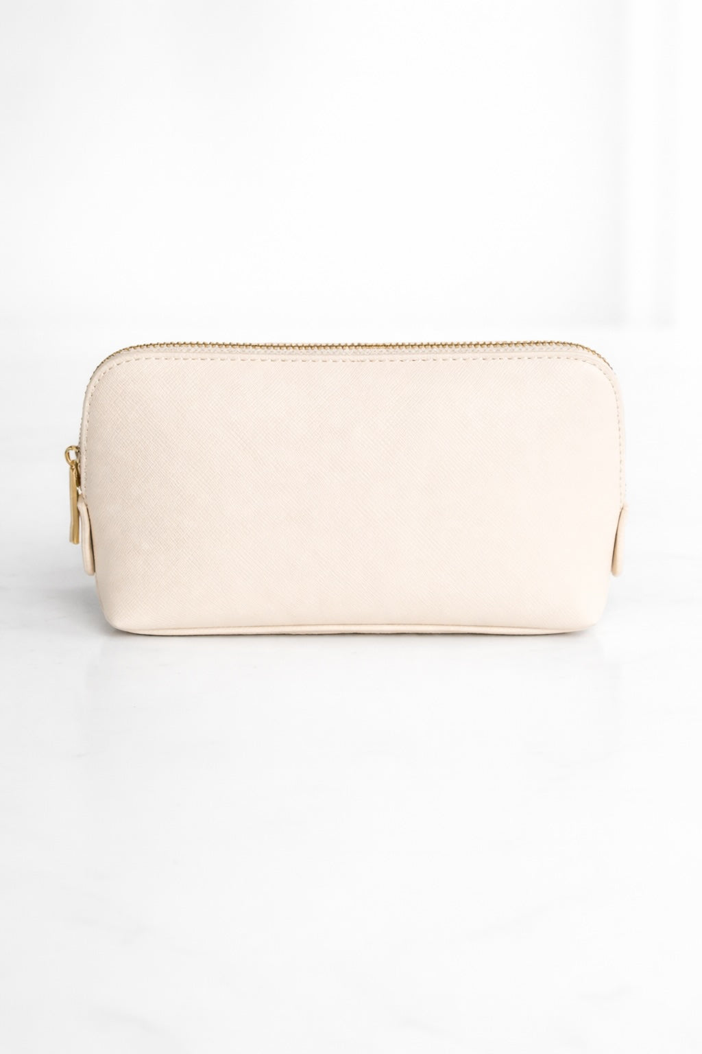 Beige Kosmetiktasche mit goldenem Reißverschluss auf hellem, neutralem Hintergrund
