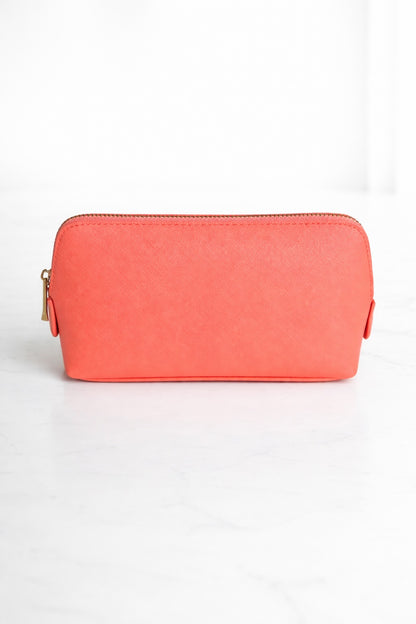 Coral Kosmetiktasche mit goldenem Reißverschluss auf hellem, neutralem Hintergrund