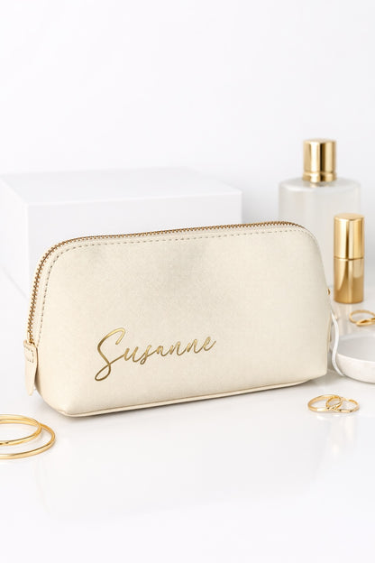 Personalisierte Kosmetiktasche in Creme mit goldener Aufschrift „Susanne“ auf hellem Hintergrund mit Beauty-Accessoires