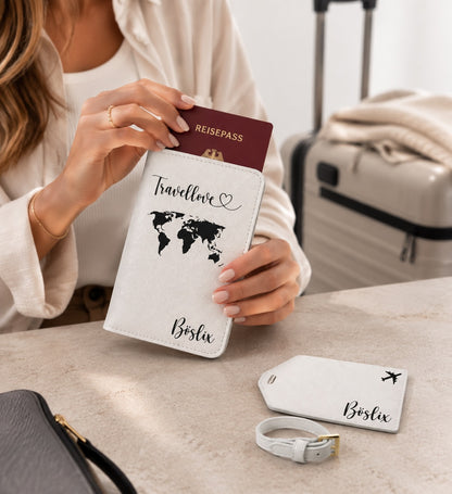 Ästhetisches Lifestyle-Foto einer Frau, die gerade einen Reisepass in eine personalisierte weiße Reisepasshülle mit Weltkartenmotiv steckt. Auf dem Tisch liegen ein passender Kofferanhänger und die Schnalle, im Hintergrund sind unscharf gepackte Koffer zu sehen.