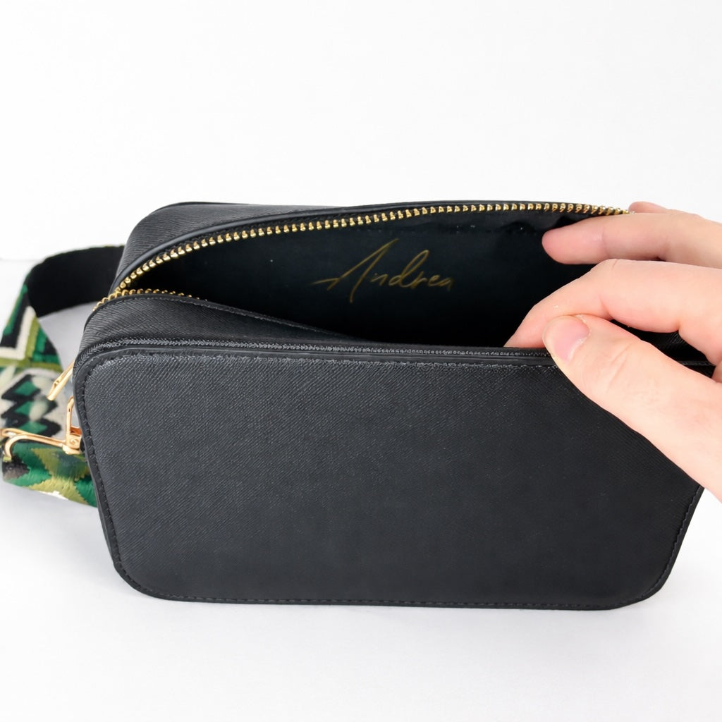 Schwarze Crossbody Tasche aus Kunstleder mit geöffnetem Reißverschluss und personalisiertem Namen im Innenfach (Beispiel Andrea), moderne Umhängetasche für Damen.