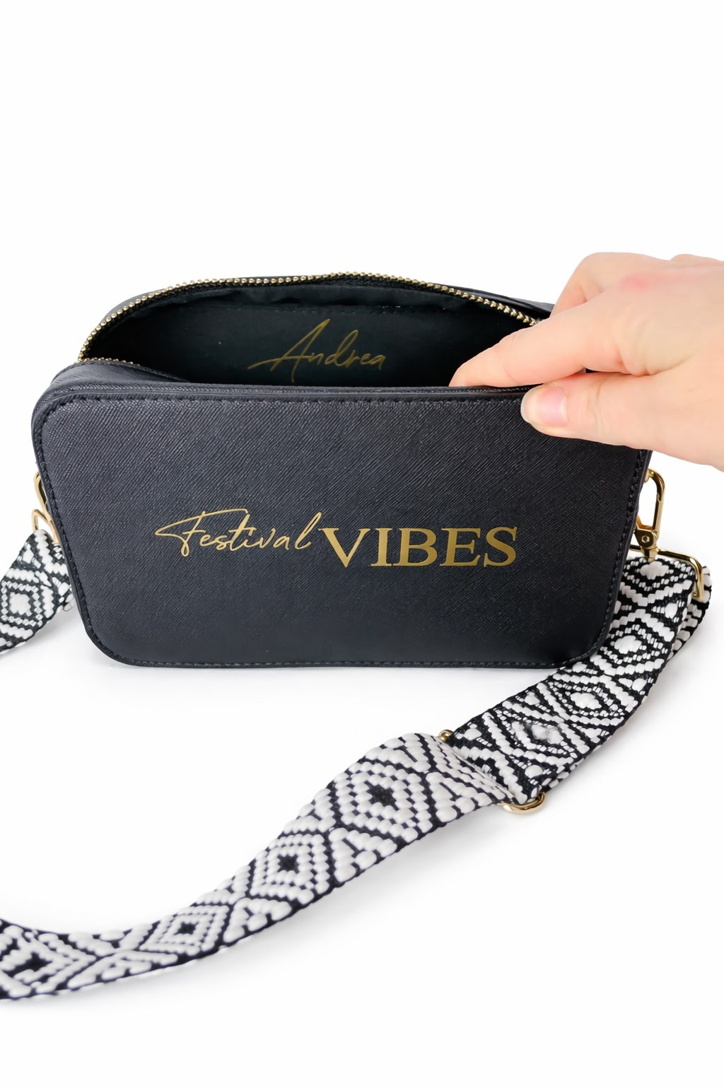 Personalisierte schwarze Umhängetasche „Festival Vibes“ mit breitem gemustertem Taschengurt und geöffnetem Reißverschluss auf hellem neutralem Hintergrund.