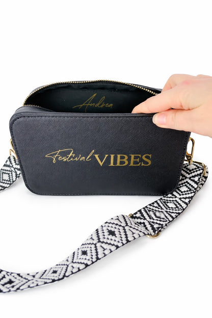 Personalisierte schwarze Umhängetasche „Festival Vibes“ mit breitem gemustertem Taschengurt und geöffnetem Reißverschluss auf hellem neutralem Hintergrund.