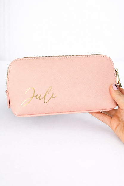 Rosa personalisierte Kosmetiktasche mit Name ‚Juli‘ in Gold, gehalten vor hellem, minimalistischem Hintergrund