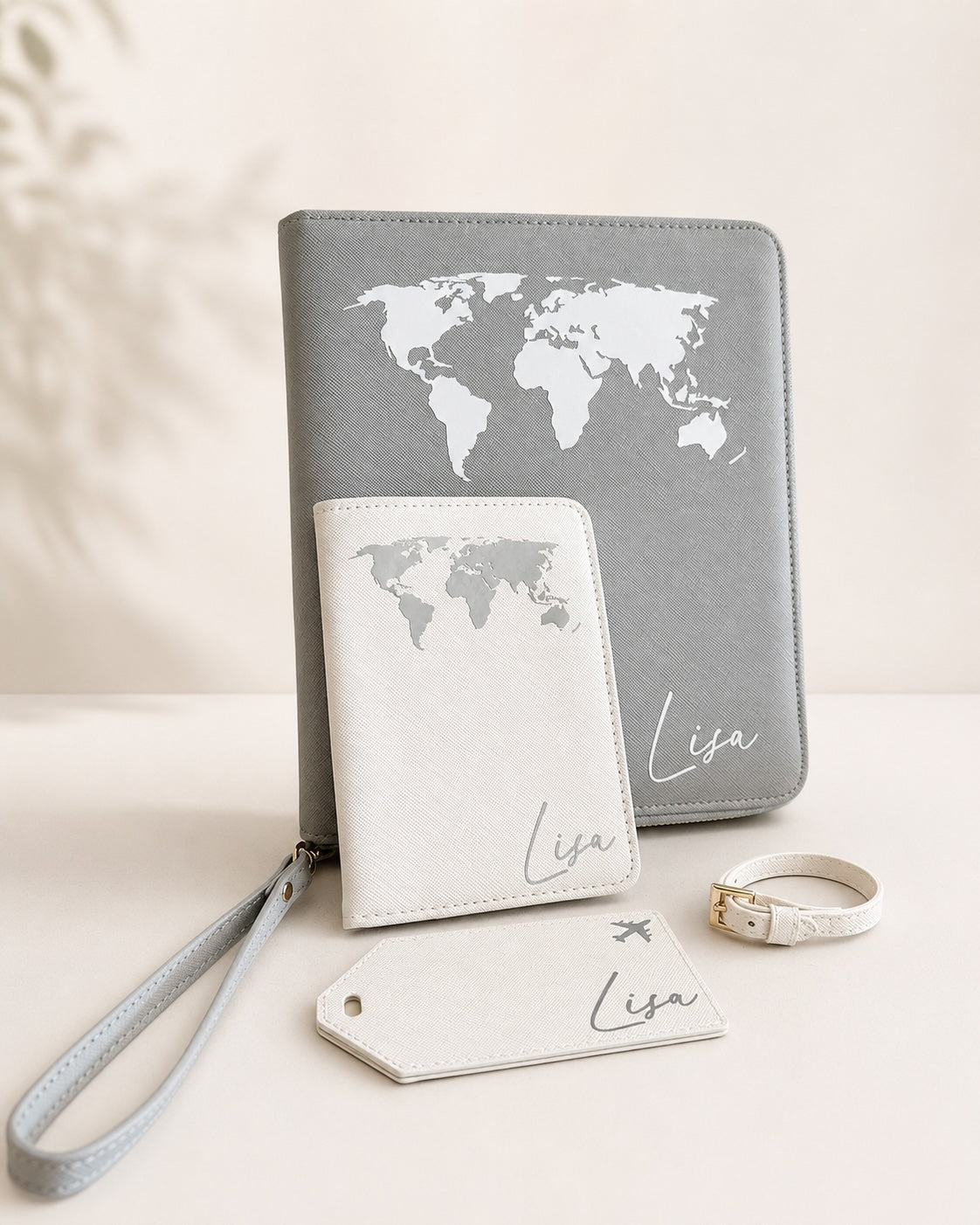 Personalisiertes Reiseaccessoire-Set mit grauem Reiseetui, weißer Reisepasshülle, Kofferanhänger und Namensaufdruck Lisa auf hellem neutralem Hintergrund.