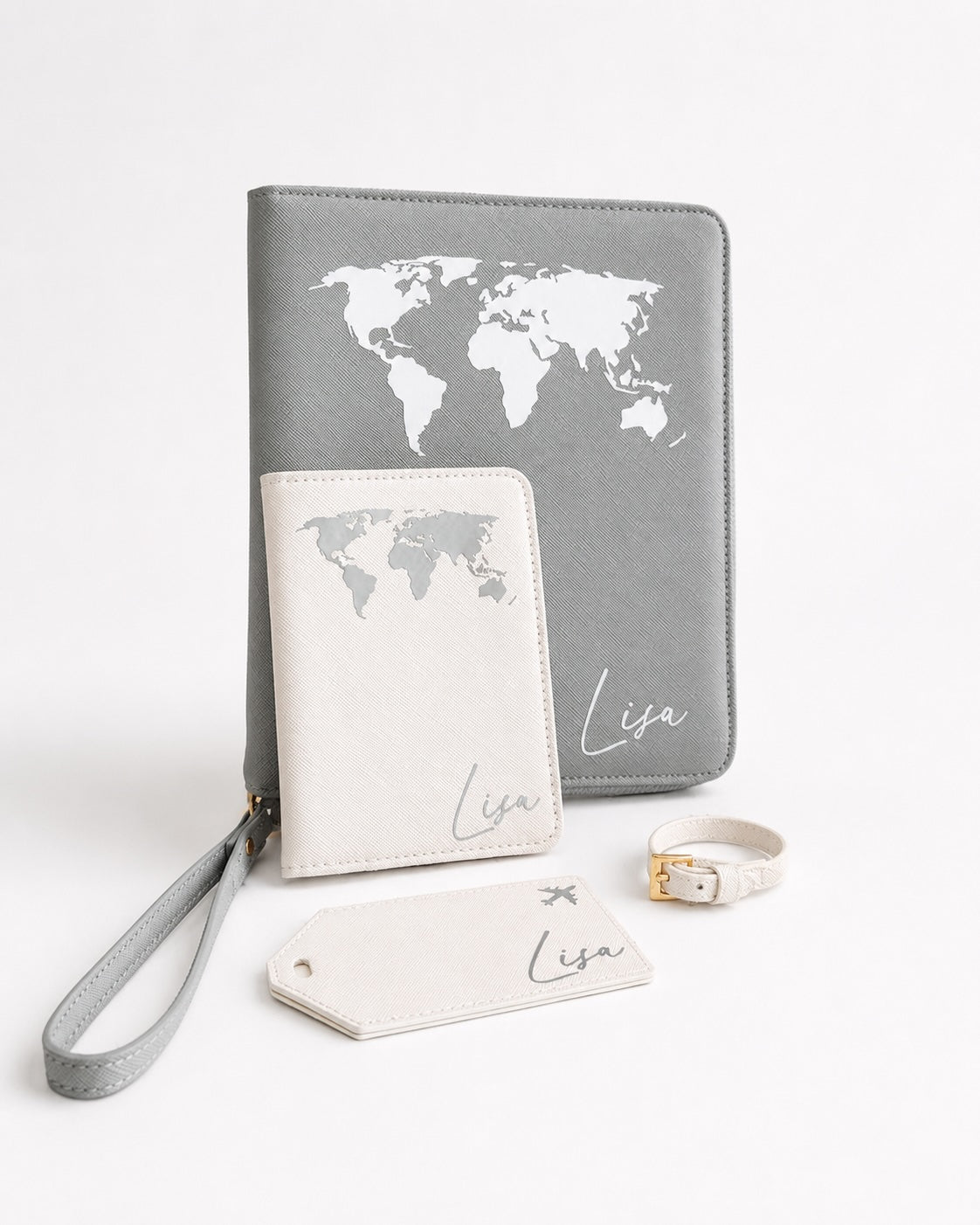 Personalisiertes Reiseaccessoires Set in Grau und Creme mit Weltkartenmotiv, Reiseorganizer, Reisepasshülle, Kofferanhänger und Armband auf hellem Hintergrund.