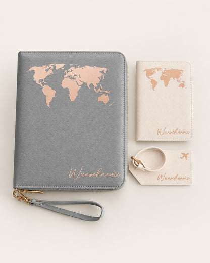 Flaches Produktfoto eines personalisierten Reiseaccessoire-Sets mit Dokumentenmappe, Reisepasshülle, Gepäckanhänger und Handschlaufe in Grau und Creme mit Roségold-Weltkartenaufdruck auf hellem neutralem Hintergrund.