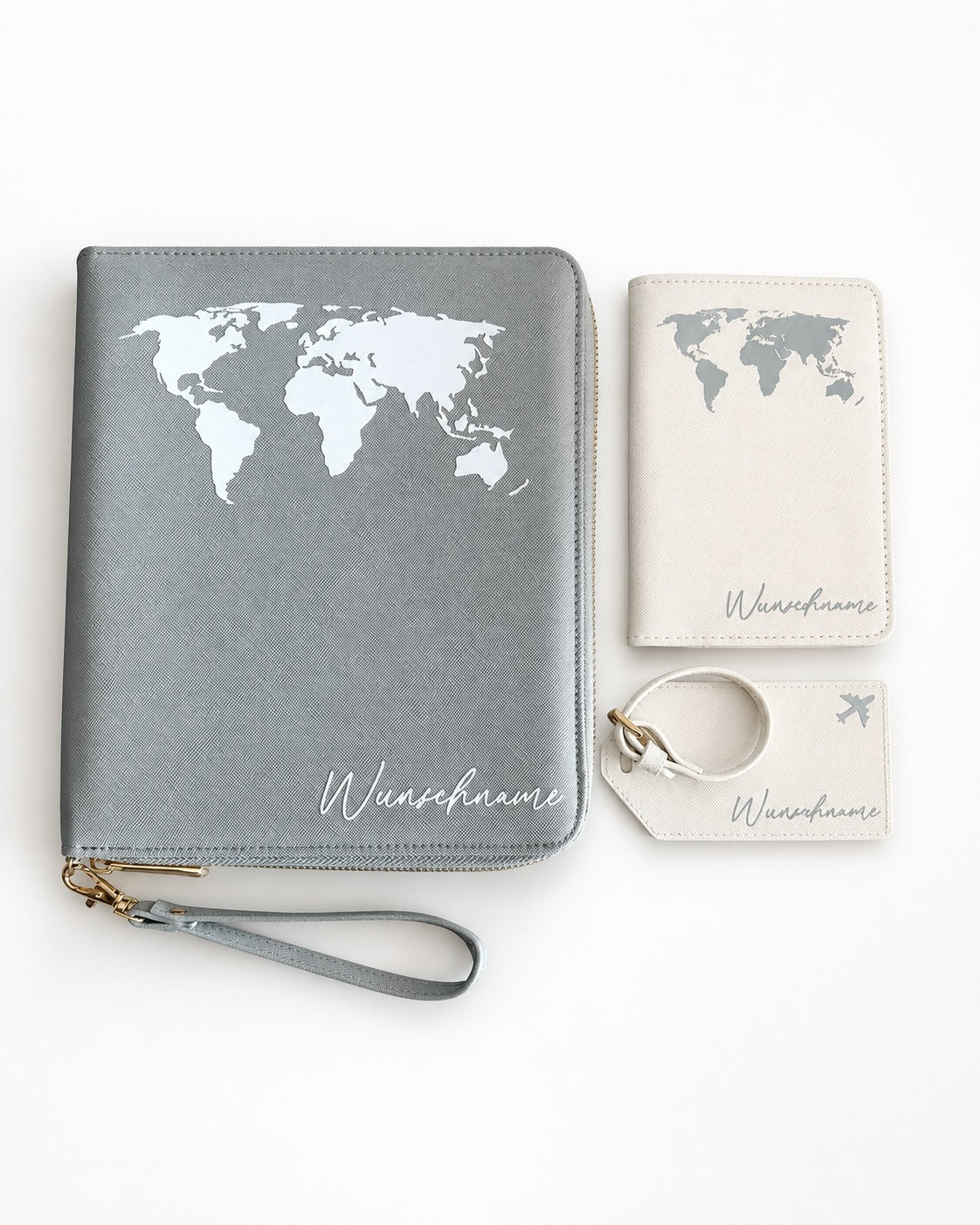 Flatlay eines personalisierten Reiseaccessoire-Sets mit grauem Organizer, cremefarbener Reisepasshülle und Kofferanhänger, jeweils mit weißem Weltkarten-Design und Namensschriftzug, sauber auf hellem neutralem Hintergrund arrangiert.