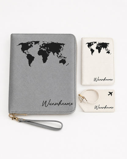 Flatlay eines personalisierten Reiseaccessoire-Sets mit grauem Organizer, cremefarbener Reisepasshülle und Kofferanhänger, jeweils mit schwarzer Weltkarten-Grafik und Namensaufdruck, sauber auf hellem neutralem Hintergrund arrangiert.
