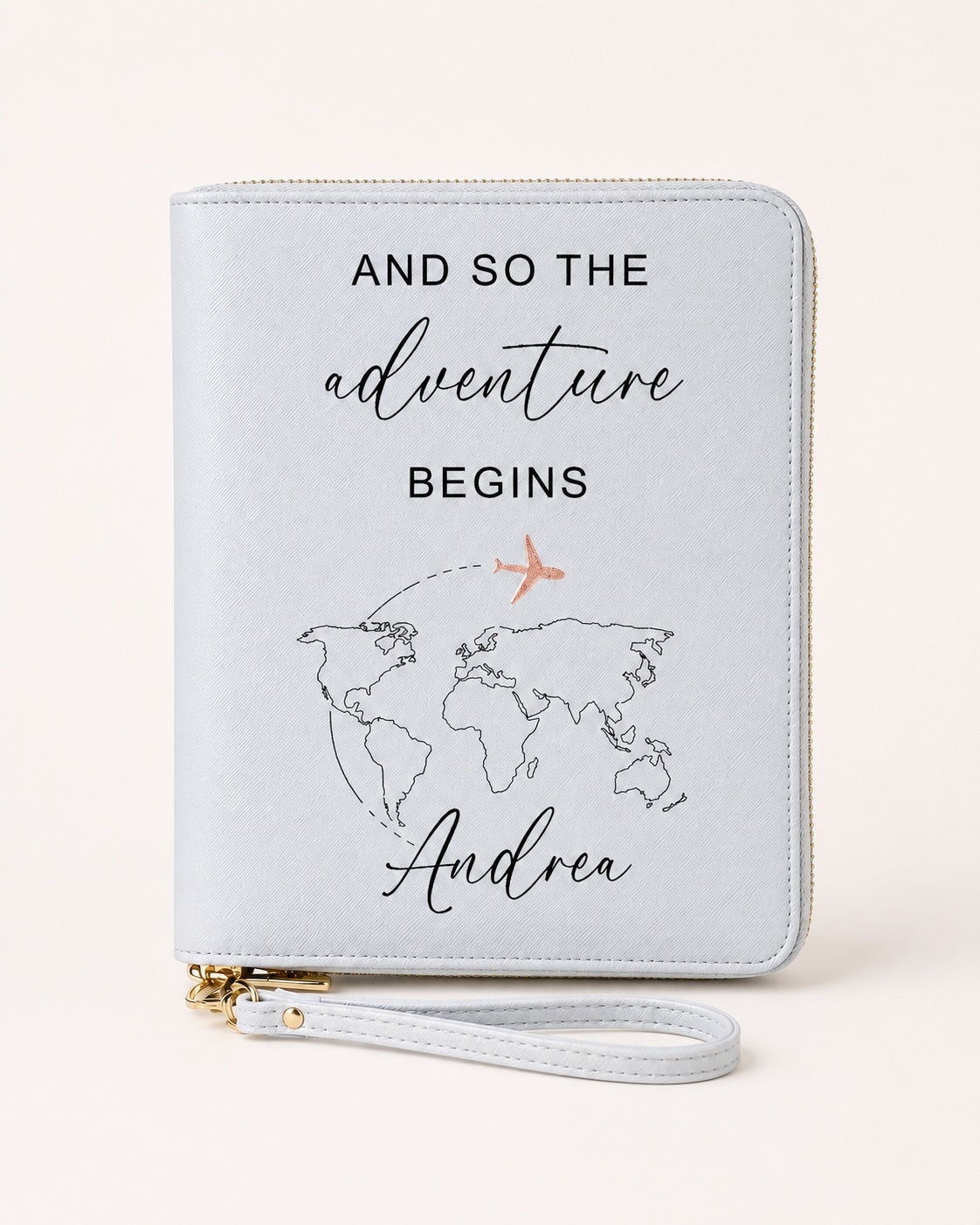 Weißer personalisierter Reiseorganizer mit der Aufschrift „And so the adventure begins“, Weltkarten-Motiv, Name „Andrea“ und Flugzeug in Roségold.