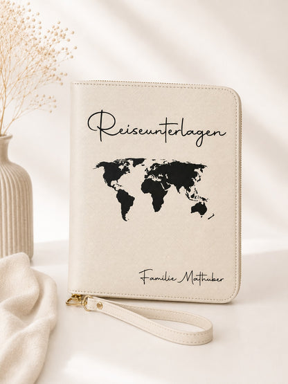 Beiger personalisierter Reiseorganizer mit schwarzem Schriftzug „Reiseunterlagen“, schwarzer Weltkarte und der Personalisierung „Familie Mathuber“ vor hellem, neutralem Hintergrund.