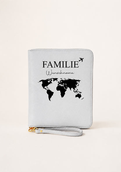 Personalisierter grauer Reiseorganizer mit Familienmotiv, Wunschname, Weltkarte und Flugzeugsymbol auf einem hellen, neutralen Hintergrund. Das Produkt steht mittig im Fokus und eignet sich als Reiseorganizer für Familien.