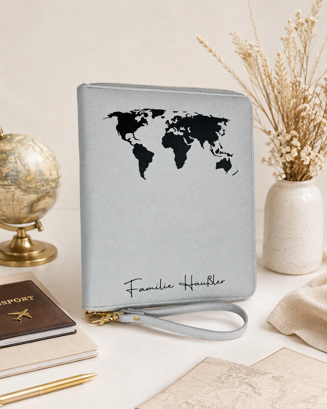 Personalisierter Reiseorganizer in Grau mit schwarzer Weltkarte und Familiennamen, dekoriert mit Reiseaccessoires
