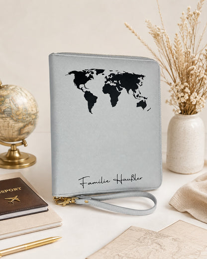 Personalisierter Reiseorganizer in Grau mit schwarzer Weltkarte und Familiennamen, dekoriert mit Reiseaccessoires