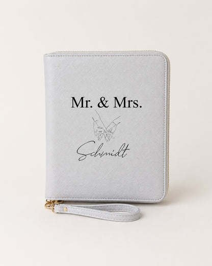 Personalisierter hellgrauer Reiseorganizer mit „Mr. & Mrs. Schmidt“, Handmotiv und schwarzem Aufdruck auf neutralem Hintergrund.