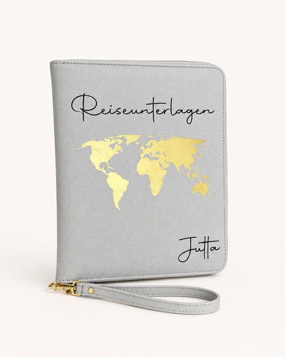 Grauer personalisierter Reiseorganizer mit goldenem Weltkarten-Motiv, schwarzem Schriftzug „Reiseunterlagen“ und dem Namen Jutta vor hellem, neutralem Hintergrund.
