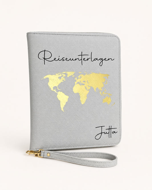 Grauer personalisierter Reiseorganizer mit goldenem Weltkarten-Motiv, schwarzem Schriftzug „Reiseunterlagen“ und dem Namen Jutta vor hellem, neutralem Hintergrund.