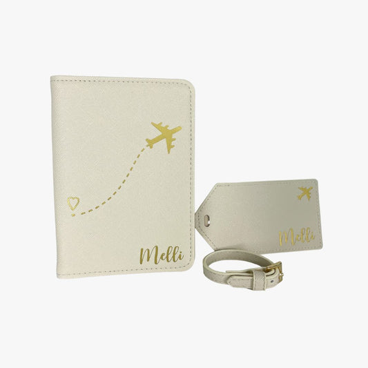 Personalisierte beige Reisepasshülle mit goldenem Flugzeug-Design und Herz sowie passendem Kofferanhänger mit Namen „Melli“, aus veganem Saffiano-Leder.