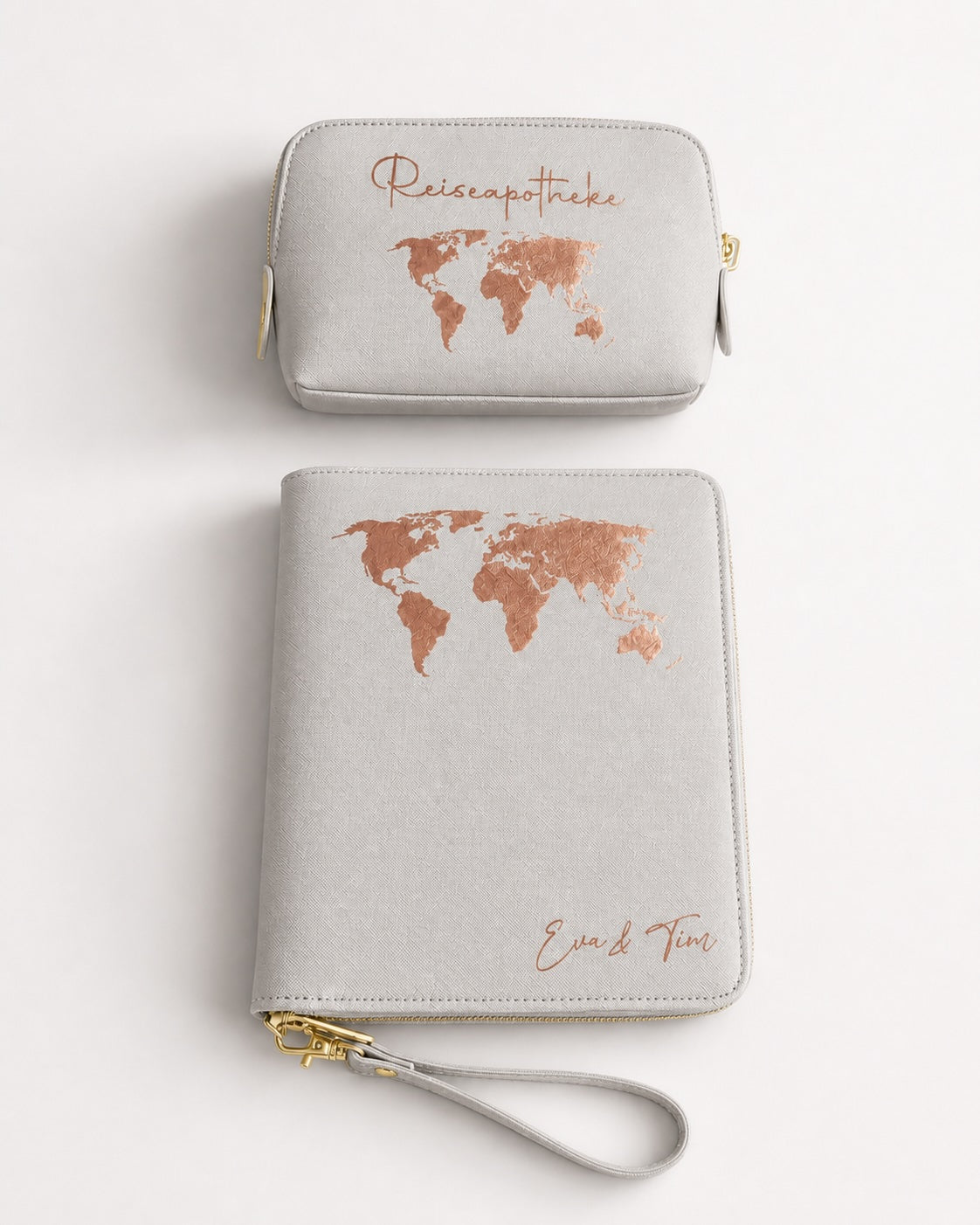 Produktbild eines personalisierten Reisesets in Hellgrau mit leicht schimmerndem Roségold-Aufdruck, bestehend aus Reiseapotheke und Organizer mit goldfarbener Schnalle vor hellem, weißem Hintergrund.
