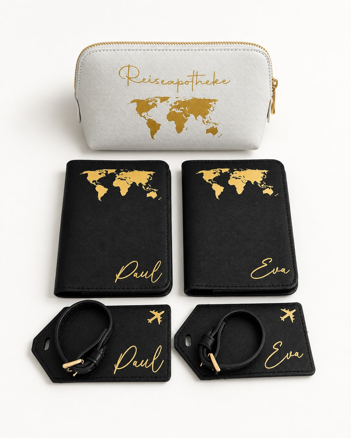 Produktbild eines personalisierten Reisesets mit hellgrauer Reiseapotheke, schwarzen Passhüllen und Kofferanhängern mit goldfarbenem Aufdruck vor hellem Hintergrund.