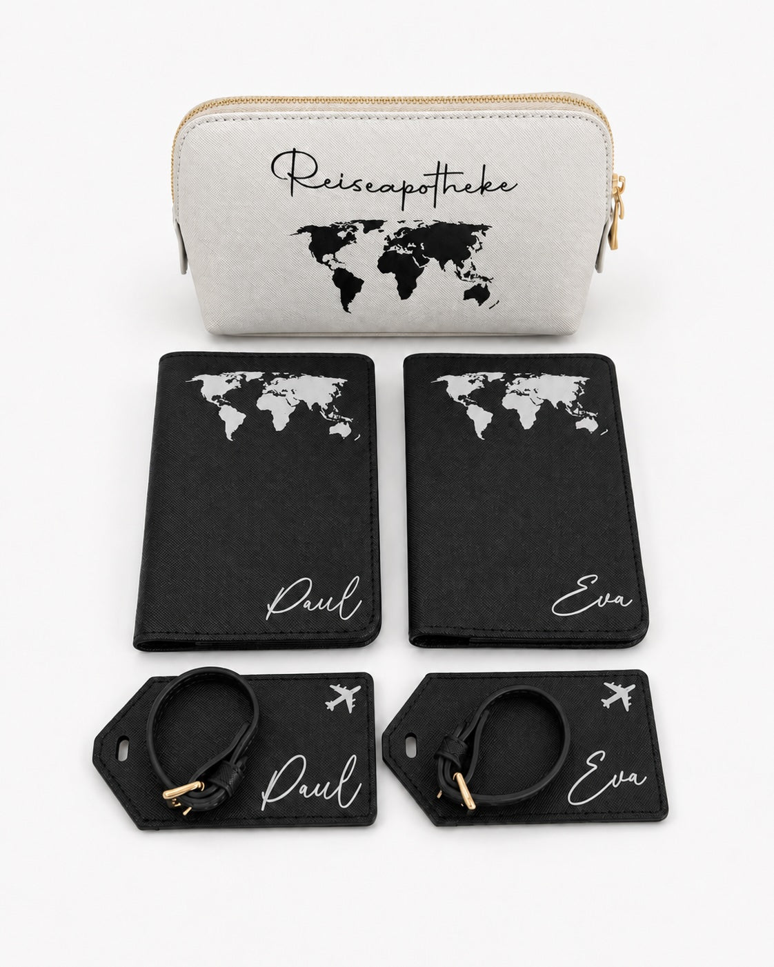 Personalisiertes Reiseset mit schwarzer Reisepasshülle und Kofferanhängern mit weißem Weltkarten-Aufdruck sowie hellgrauer Reiseapotheke mit schwarzem Aufdruck auf hellem, minimalistischem Hintergrund.