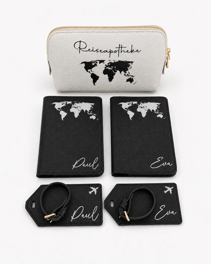 Personalisiertes Reiseset mit schwarzer Reisepasshülle und Kofferanhängern mit weißem Weltkarten-Aufdruck sowie hellgrauer Reiseapotheke mit schwarzem Aufdruck auf hellem, minimalistischem Hintergrund.