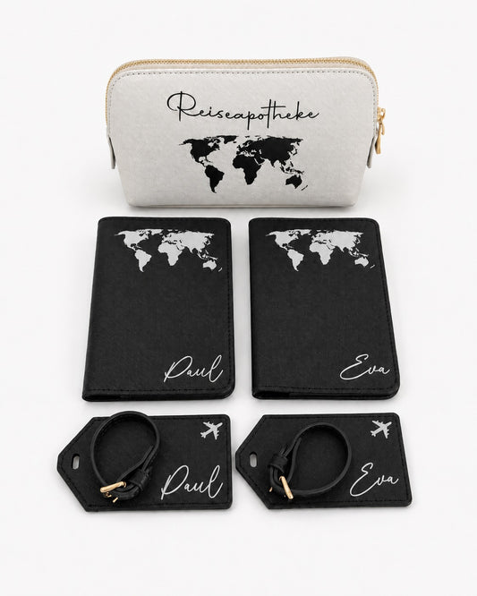 Personalisiertes Reiseset mit schwarzer Reisepasshülle und Kofferanhängern mit weißem Weltkarten-Aufdruck sowie hellgrauer Reiseapotheke mit schwarzem Aufdruck auf hellem, minimalistischem Hintergrund.