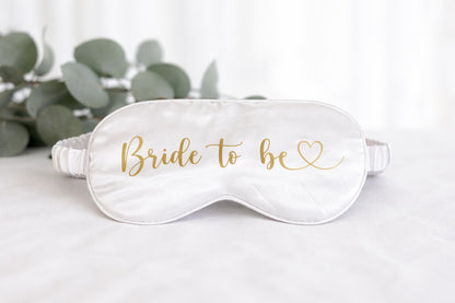Weiße Schlafmaske mit goldener Aufschrift „Bride to be“ für das Getting Ready der Braut am Hochzeitstag.