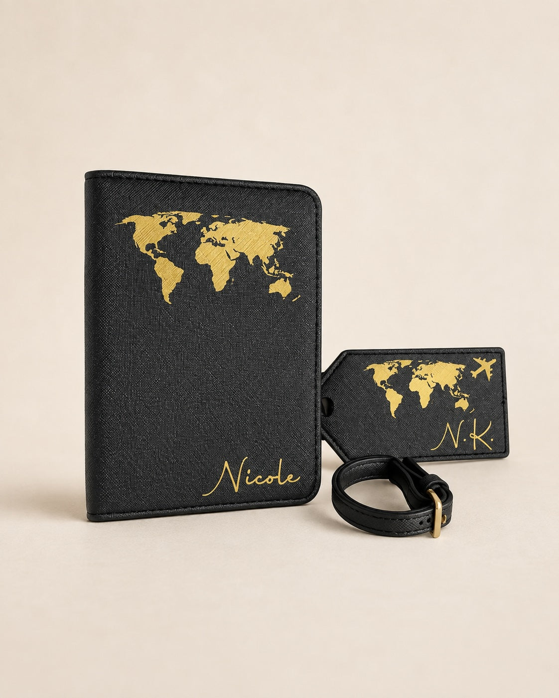 Personalisierte schwarze Reisepasshülle mit passendem Kofferanhänger und Gepäckriemen. Das Reiseaccessoire-Set ist mit einer goldenen Weltkarte, Flugzeugmotiv und den Namen „Nicole“ sowie den Initialen „N.K.“ verziert. Hochwertiges Reise-Set auf neutralem beigefarbenem Hintergrund.