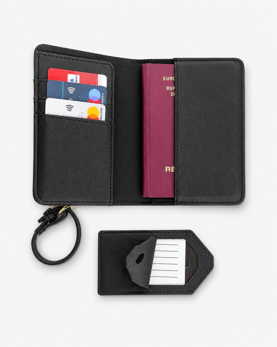 Offenes schwarzes Reiseportemonnaie auf hellem, neutralem Hintergrund. Im Inneren befinden sich Kartenfächer mit Kreditkarten sowie ein bordeauxfarbener Reisepass in der rechten Einsteckhülle. Links ist eine Handschlaufe befestigt. Darunter liegt ein schwarzer Gepäckanhänger mit Einsteckkarte, der teilweise geöffnet ist. Produktfoto im minimalistischen Stil für einen Online-Shop.
