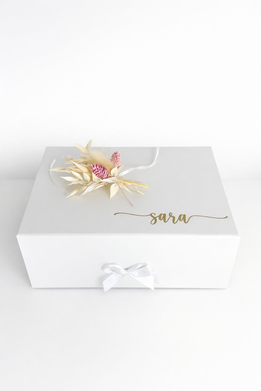 Weiße personalisierte Geschenkbox mit Trockenblumen und Name „Sara“ auf minimalistischem hellem Hintergrund