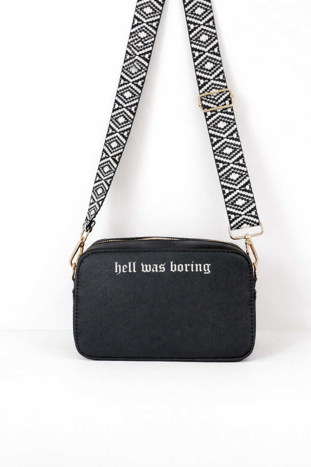 Schwarze Crossbody Umhängetasche für Damen mit Aufdruck „hell was boring“ und gemustertem Taschengurt.